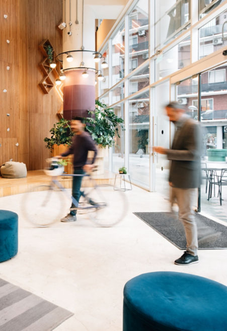 Man with bicycle and man holding a phone going through a lobby - KONE